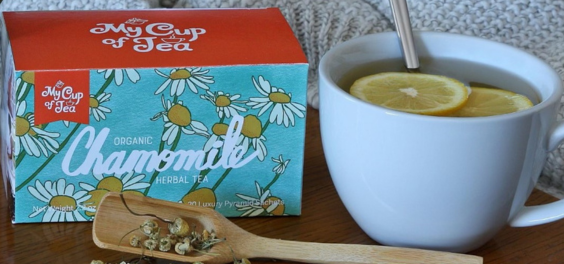 A box of Organic Chamomile tea sachets and a cup of chamomile tea with lemon. 
