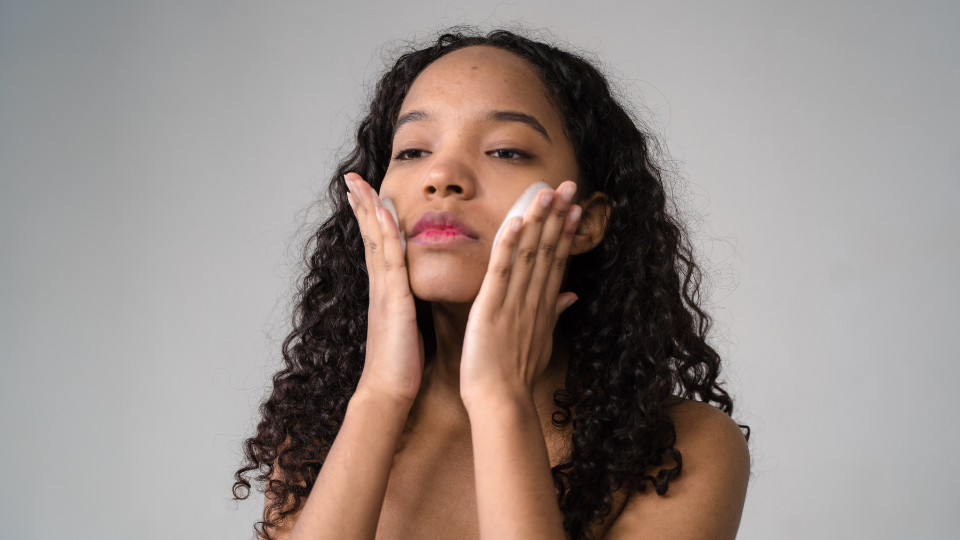 Black woman with shoulder length hair applying skincare.